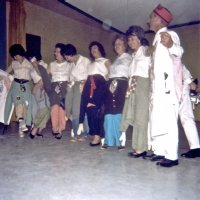 05/64 - District 4C-4 Convention, Hoberg’s Resort, Lake County - Line dancing with coats buttoned around their waists; perhaps a Tail Twister skit. L to R: Estelle Bottarini, wife, Eva Bello, wife, wife, Irene Tonelli, wife, and Charlie Bottarini.