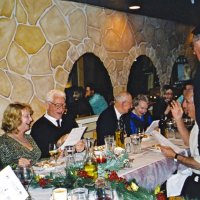 12/8/04 - Club Christmas Party, Ristorante Mar, Pacifica - Members and guests singing Christmas carols, led by Handford Clews (standing). From left: guest, Al Gentile, Ted & Vernelle Wildenradt, and a guest. Charlie Bottarini is seated just below Handford.