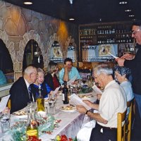 12/8/04 - Club Christmas Party, Ristorante Mar, Pacifica - Members and guests singing Christmas carols, led by Handford Clews (standing). From left: Al Gentile, Ted & Vernelle Wildenradt, and a guest couple. Charlie & Estelle Bottarini are seated just below Handford.