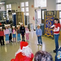 12/15/06 - Christmas at Mission Educational Center, Police Officer “Nacho” Martinez as Santa - Santa, and others, look on as students and their teacher sing a song for them.