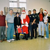 12/15/06 - Christmas at Mission Educational Center, Police Officer “Nacho” Martinez as Santa - L to R: Lions Bill Graziano and Bob Fenech, principal Deborah Molof, Santa, his Police Officer escorts, and others, all pose after all the presentations are complete.