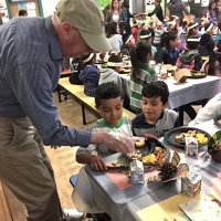 11-18-16 - MEC Thanksgiving Luncheon, Mission Education Center, San Francisco - Bill Graziano explains what is on the plate to a student.