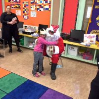 12/21/17 - Christmas with Santa, Mission Educational Center - A child happily poses with Santa before receiving her gift.
