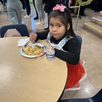 12-18-24 - 43rd Annual Lions Christmas with Santa at the Mission Education Center with Los Bomberos Firefighters - Looks like she is not quite sure about lunch, or the photo.