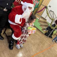 12-18-24 - 43rd Annual Lions Christmas with Santa at the Mission Education Center with Los Bomberos Firefighters - One by one, the students receive their presents from Santa, each having a quick pose after with Santa and his helper.