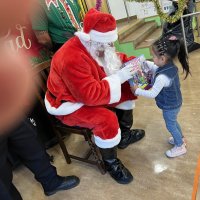 12-18-24 - 43rd Annual Lions Christmas with Santa at the Mission Education Center with Los Bomberos Firefighters - One by one, the students receive their presents from Santa, each having a quick pose after with Santa and his helper.