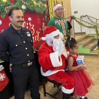 12-18-24 - 43rd Annual Lions Christmas with Santa at the Mission Education Center with Los Bomberos Firefighters - One by one, the students receive their presents from Santa, each having a quick pose after with Santa and his helper.