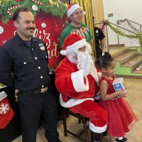 12-18-24 - 43rd Annual Lions Christmas with Santa at the Mission Education Center with Los Bomberos Firefighters - One by one, the students receive their presents from Santa, each having a quick pose after with Santa and his helper.