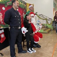 12-18-24 - 43rd Annual Lions Christmas with Santa at the Mission Education Center with Los Bomberos Firefighters - One by one, the students receive their presents from Santa, each having a quick pose after with Santa and his helper.