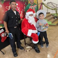 12-18-24 - 43rd Annual Lions Christmas with Santa at the Mission Education Center with Los Bomberos Firefighters - One by one, the students receive their presents from Santa, each having a quick pose after with Santa and his helper.